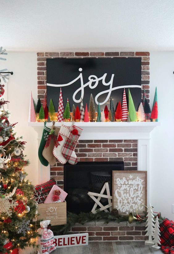 a bright Christmas mantel with bold bottle cleaner trees, lights, bright stockings and plaid pillows brings festive spirit