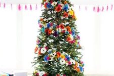 a bright Christmas tree with orange, pink, blue, white and yellow faux blooms and a wooden star topper is gorgeous