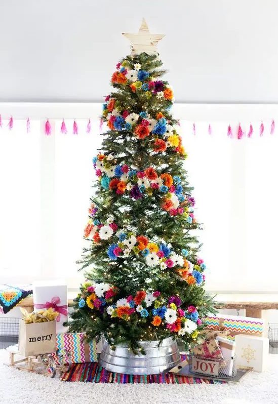a bright Christmas tree with orange, pink, blue, white and yellow faux blooms and a wooden star topper is gorgeous