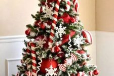 a bright and chic Christmas tree with candy canes, red ornaments, snowflakes, twigs and berries is amazing
