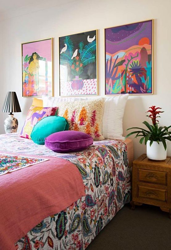 a bright maximalist bedroom with wooden furniture, a colorful gallery wall and bright textiles and bedding is amazing