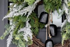 a catchy Christmas wreath of vine and flocked and usual evergreens and large black bells is a lovely and bold decoration