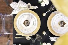 a chic black and gold tablescape with polka dots, geo prints and some white blooms are an amazing combo for hristmas