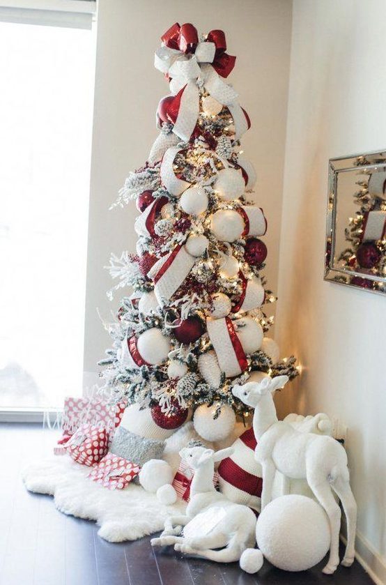 a chic flocked Christmas tree with lights, oversized red and white ornaments and matching ribbons plus a bow on top