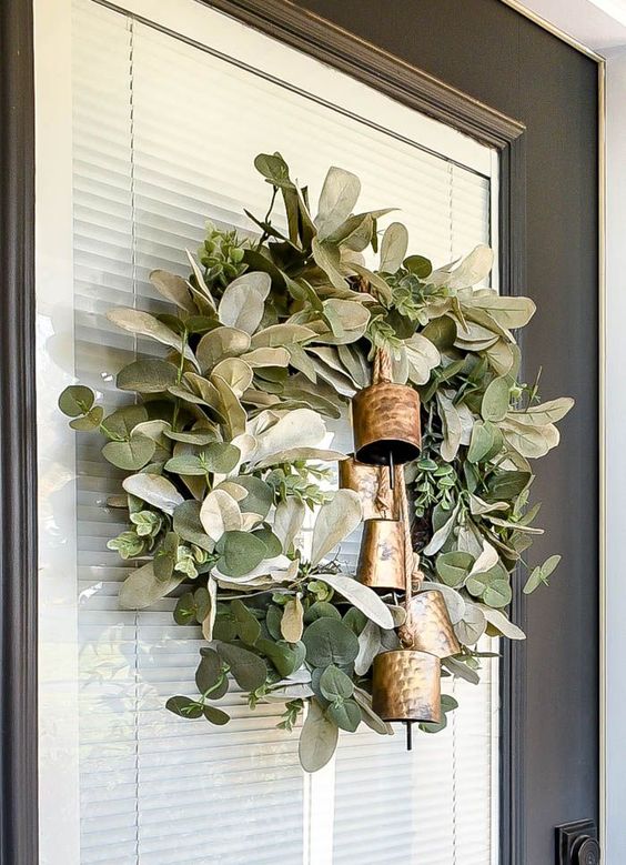 a chic winter or Christmas wreath of foliage and greenery and oversized vintage Christmas bells is an elegant decor idea