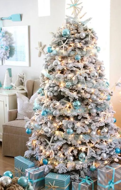 a coastal Christmas tree   a flocked one with silver, light and bright blue ornaments, lights, starfish and a star tree topper is a gorgeous idea