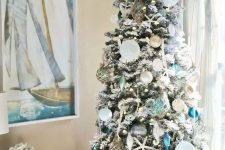 a coastal chic christas tree with navy, turquoise, mint and white Christmas ornaments, seashells, starfish and buoys