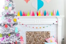 a colorful 80s inspired Christmas space with bold cardboard trees on the mantel, cardboard ornaments on the wall and a white tree with bright ornaments