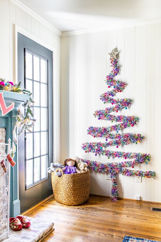 a colorful Christmas garland forming a Christmas tree on the wall and accented with mini Christmas ornaments that match