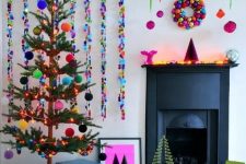 a colorful Christmas space with a bold striped rug, colorful sequin garlands and tree with bright pompoms, a bright ornament wreath and bold ornamnets hanging on ribbons is amazing