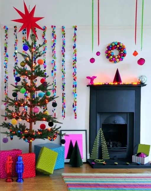 a colorful Christmas space with a bold striped rug, colorful sequin garlands and tree with bright pompoms, a bright ornament wreath and bold ornamnets hanging on ribbons is amazing
