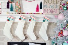 a colorful Christmas space with a neutral tree with pastel and bright ornaments, pastel felt Christmas trees, colorful gift boxes and a bright sign