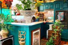a colorful maximalist kitchen with yellow walls, emerald cabinets, a colorful tile backsplash and lots of potted plants