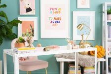 a colorful working space with turquoise walls, a blush chair, a white desk, a colorful rug and a bright gallery wall