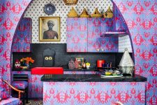 a crazy maximalist kitchen with purple and pink wallpaper all over, a gold pendant lamp, black tiles and stone countertops and a statement artwork