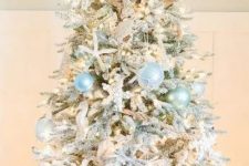 a dreamy coastal Christmas tree with light blue and mint buoy ornaments, sea horses, starfish, lights and a burlap bow on top