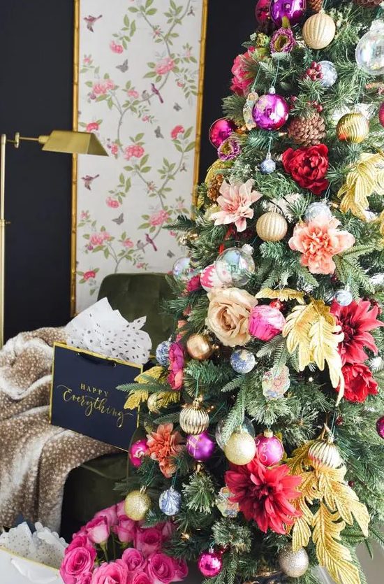 a glam Christmas tree decorated with pink, red, peachy and yellow blooms, leaves, shiny metallic and bold ornament and pinecones