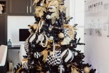 a glam Christmas tree with black, white and gold decor, monograms, ornaments and gold leaves and branches