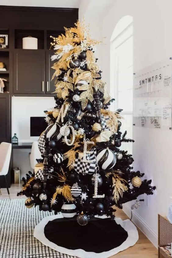 a glam Christmas tree with black, white and gold decor, monograms, ornaments and gold leaves and branches