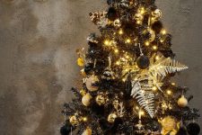 a glam black Christmas tree with gold and black ornaments, leaves, ribbon and lights is amazing