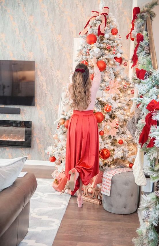 a glam flocked Christmas tree with lights, oversized red ornaments, metallic ones and fabric bows plus fabric blooms is a gorgeous idea