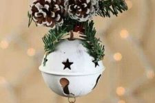 a gorgeous Christmas ornament of a white Christmas bell, a snowflake and some evergreens and snowy pinecones is all cool