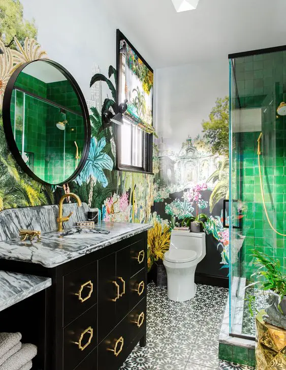 a gorgeous maximalist bathroom with botanical motifs, with printed tiles, green ones in the shower, bold floral wallpaper and a black vanity