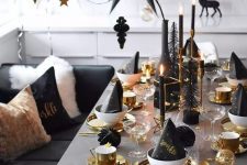 a gorgeous silver, gold and black Christmas tablescape with gold chargers, cutlery, mugs, candleholders and black candles plus an oversized black paper star