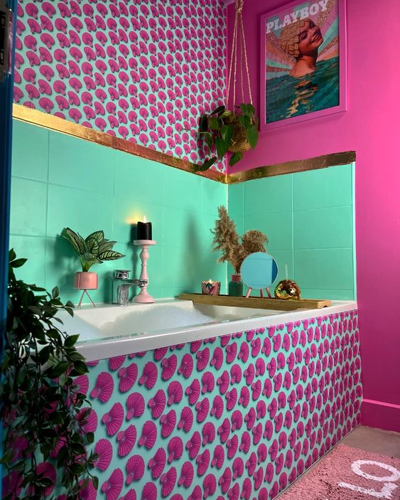 a jaw dropping bathroom ith a hot pink wall and bold printed panels, bold green tiles, touches of gold and some potted plants