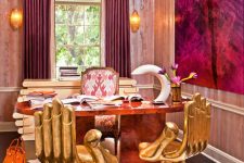 a jaw-dropping maximalist home office wiht a patterned ceiling, pink wallpaper, a stone desk, gold hand-shaped chairs, a statement artwork and curtains that echo with it