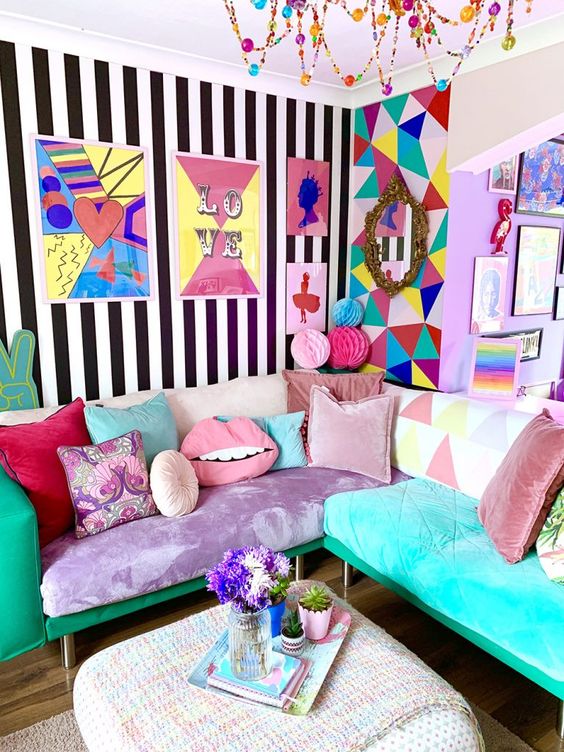 a jaw dropping maximalist living room with mismatching walls, a sectional that includes various upholstery and pillows, a colorful chandelier and accessories