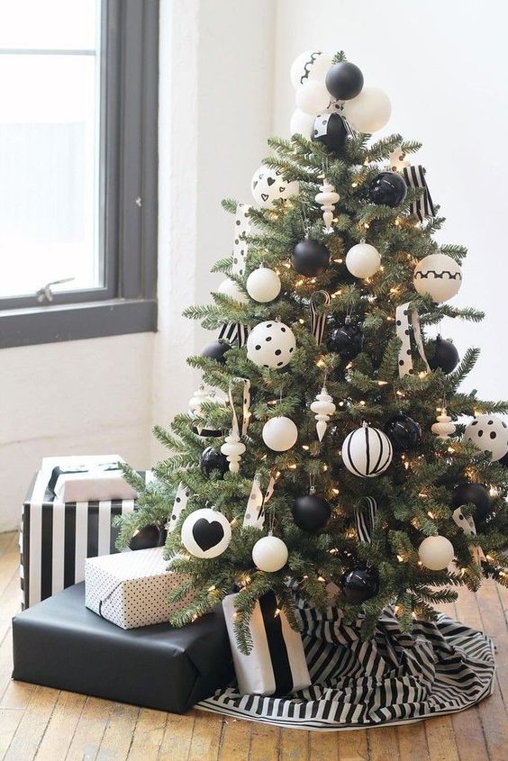 a lovely Christmas tree with black and white ornaments including polka dot ones, with lights and polka dot ribbons plus a striped tree skirt