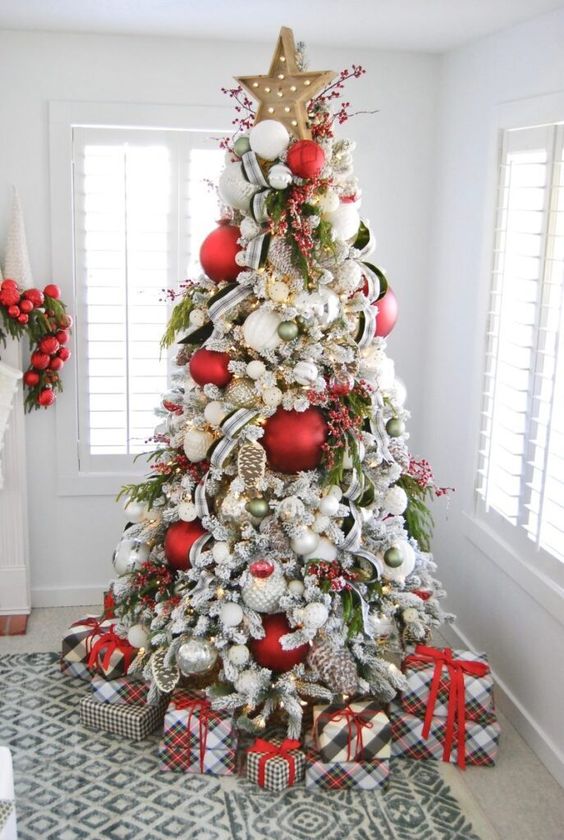 a lovely and bold Christmas tree with green, red and oversized white, silver ornaments, lights, a marquee star on top and some ribbons