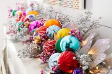 a mantel decorated with a pre-lit colorful Christmas ornament garland, with faux berries and silver leaves is a cool