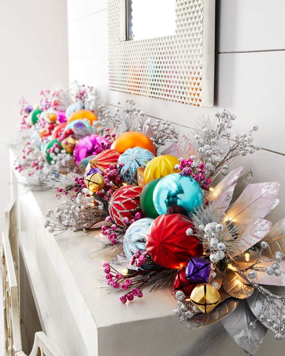 a mantel decorated with a pre lit colorful Christmas ornament garland, with faux berries and silver leaves is a cool