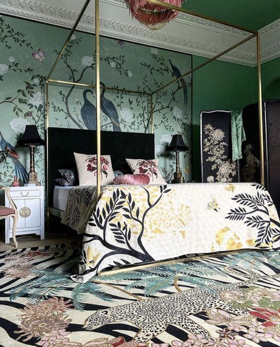 a maximalist bedroom in greens, with a canopy bed, bright printed bedding and a rug, beautiful crown molding and dark touches for more drama