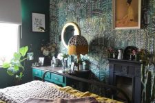 a maximalist bedroom with green walls and a botanical accent one, a black fireplace, a green console, a metal bed, bright bedding and a mirror
