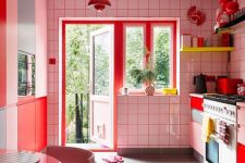 a maximalist kitchen with white tiles and red sprout, blush cabinets and red ones, neon yellow shelves and neon yellow and pink chairs