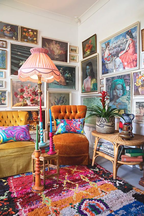 a maximalist living room with an orange and mustard chair, bright printed rugs and a jaw dropping gallery wall that takes two walls