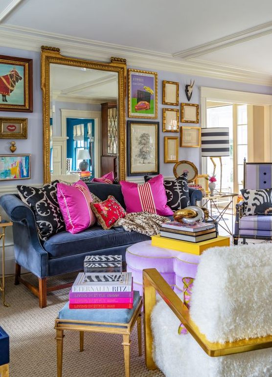 a maximalist living room with lilac walls, a navy sofa, a purple heart ottoman, colorful pillows and books and a gallery wall with a large mirror