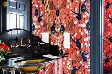 a mind-blowing maximalist bathroom with red printed wallpaper, a black, gold and clear acryl vanity, a gold sink, some lamps and a mirror wall