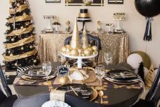 a modern and bold black and gold Christmas decor with a bright tree, balloons, hanging ornaments and a chic tablescape with printed placemats