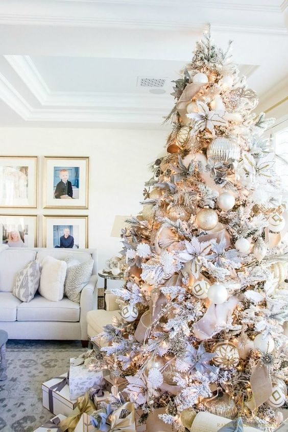 a neutral and metallic Christmas tree with oversized silver ornaments and regular shaped gold, white ones, fabric blooms and ribbons