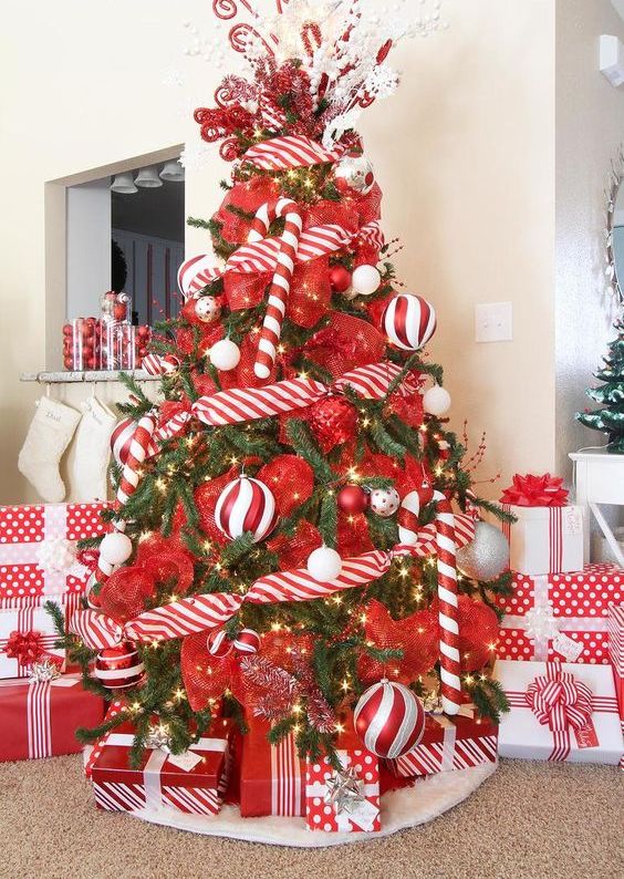 a playful Christmas tree with red and red and white ornaments plus candy cane ones is a cool and bold idea for the space