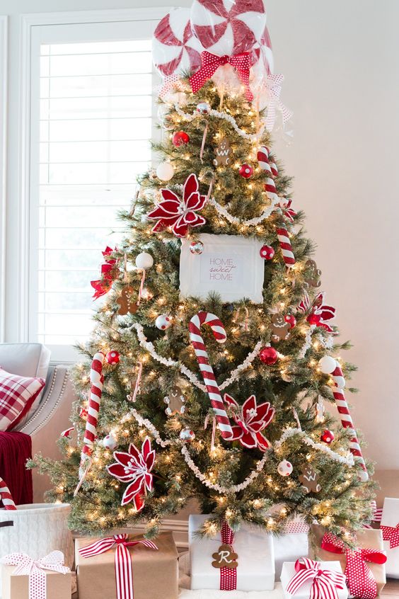 a playful Christmas tree with red and white ornaments, with red flowers and candy canes, with giant peppermints on top