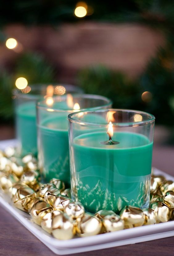a pretty Christmas decoration of a tray with gold bells and emerald candles in glasses is a lovely idea with loads of color