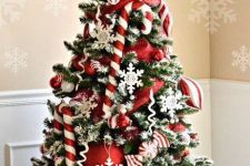 a pretty Christmas tree decorated with red ornaments, white snowflakes, candy canes and swirls on top is a very fun solution