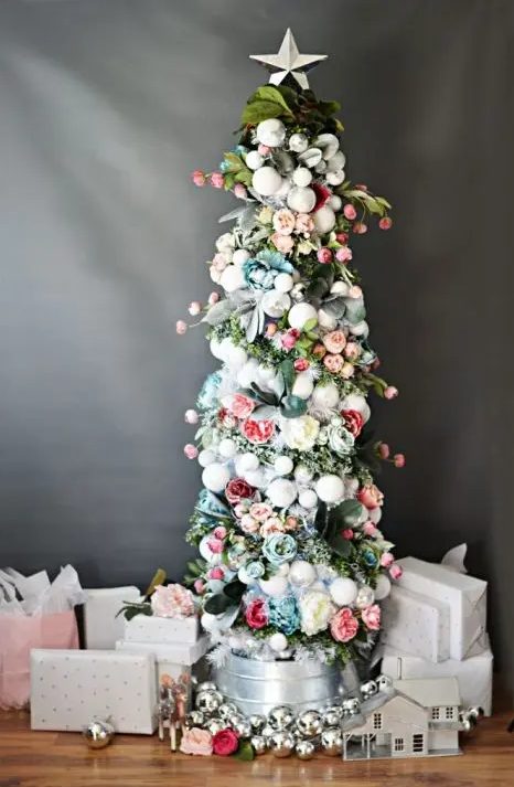 a pretty small Christmas tree decorated with white and silver ornaments, blush, pink and blue blooms and green and grey ribbons