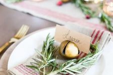 a rustic Christmas place setting with a striped napkin, twigs, a bell that holds a card is amazing for holidays