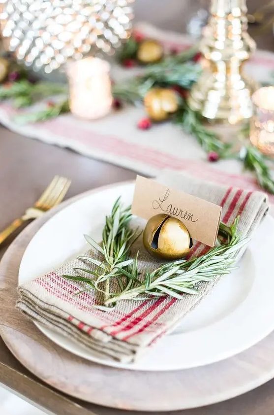 a rustic Christmas place setting with a striped napkin, twigs, a bell that holds a card is amazing for holidays